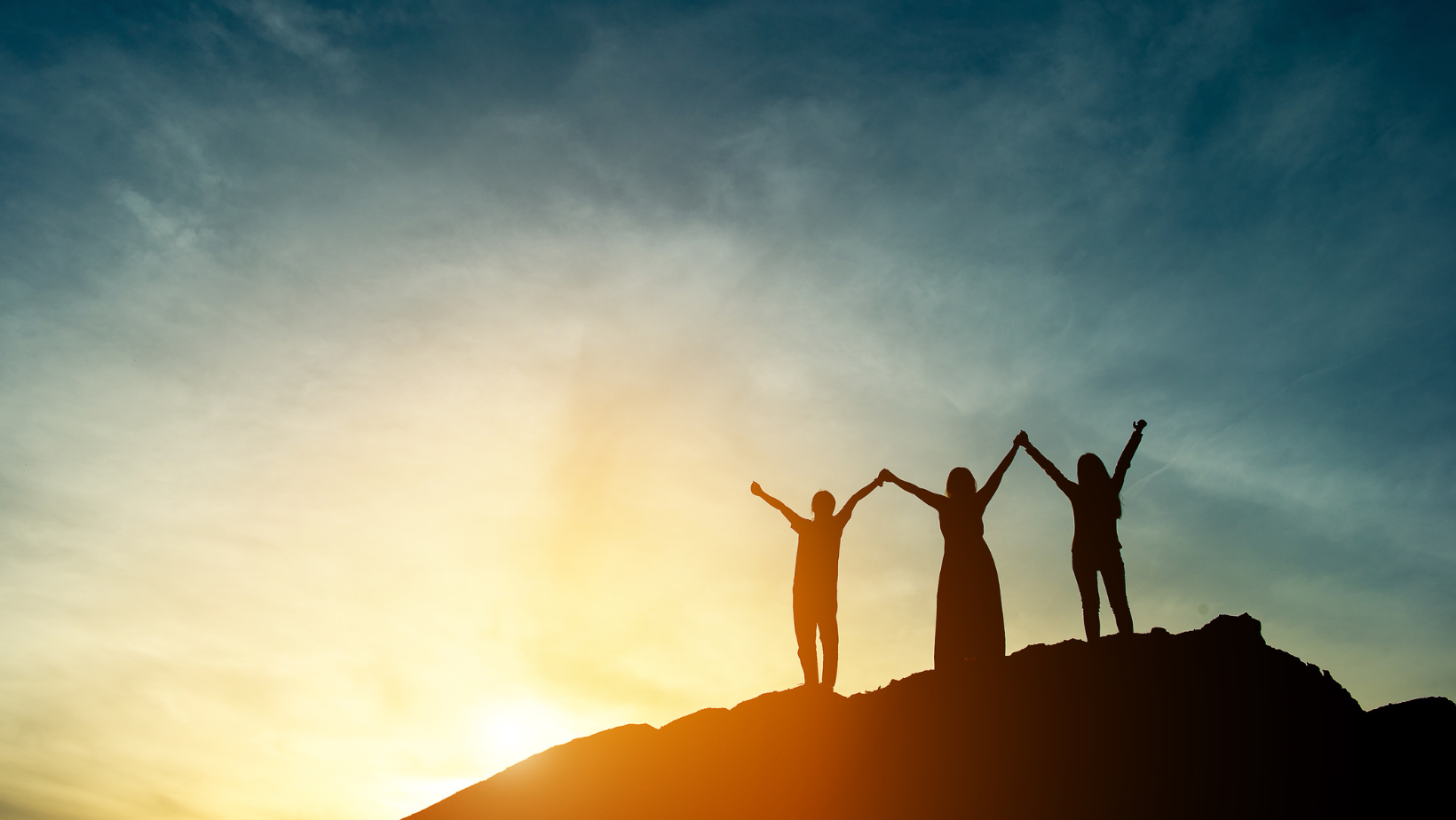 women on mountain with hands in the air